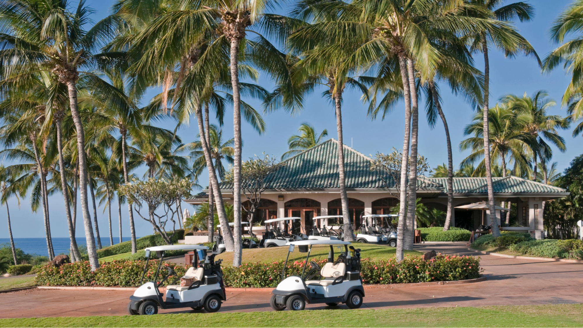 Championship golf clubhouse with palm trees and golf carts on a sunny day